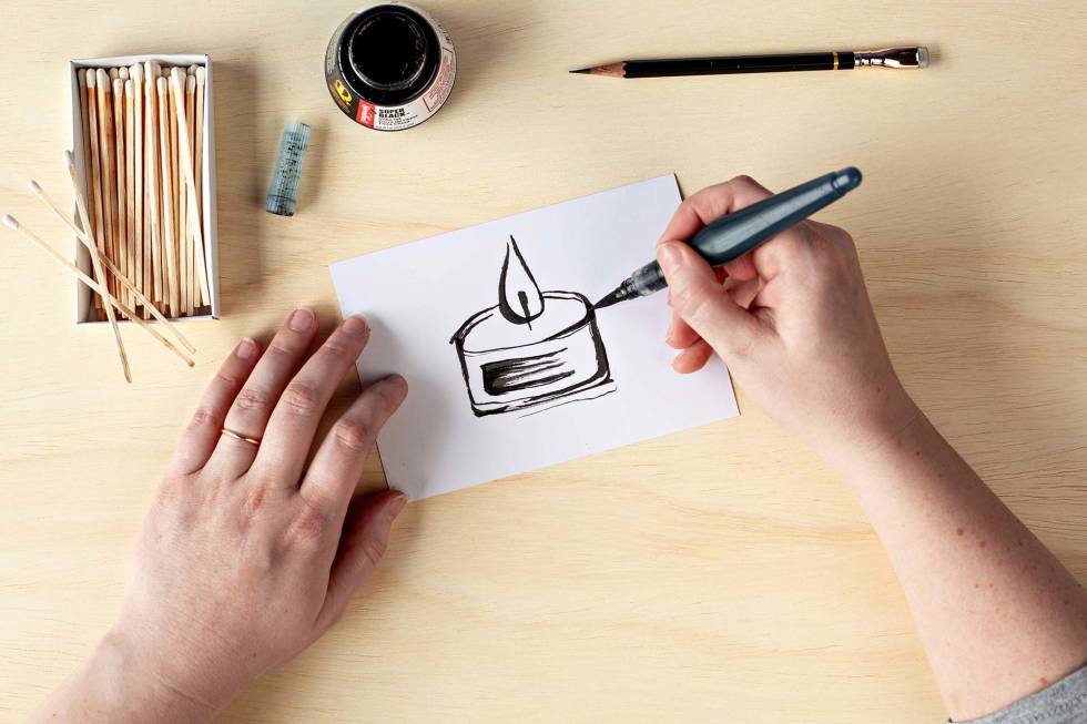 Photo of a person's hands drawing a picture of a candle with a marker